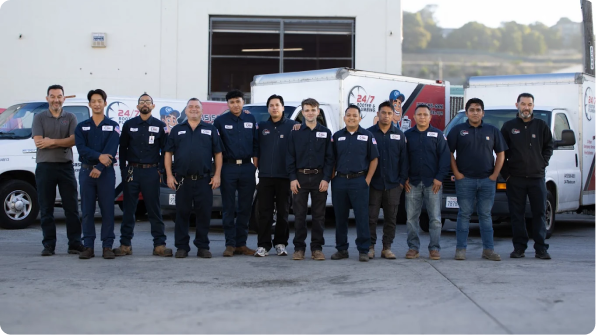 %Imagetitle% | 24/7 Rooter &Amp; Plumbing A group of twelve people in matching uniforms stand in front of service vans outside a commercial building.